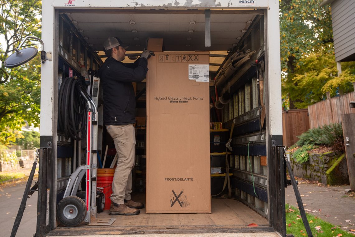 Box labeled "Hybrid Electric Heat Pump Water Heater" in the back of a truck.